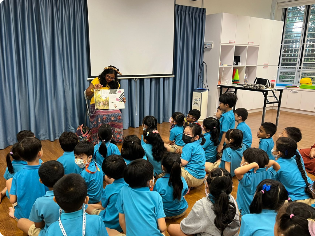 MOE Kindergarten children listen attentively as a storyteller brings a picture book to life during an engaging storytelling session.